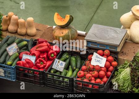 Fetta di melone poggiata sulla zucca accanto ad altri ortofrutticoli in casse al banco con bilancia di pesatura sul mercato a Cascais Portogallo Foto Stock