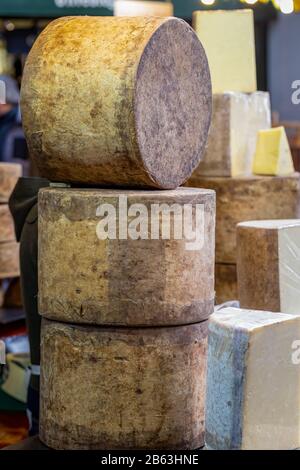 Pila di ruote di formaggio Cheddar non pastorizzate in una stalla di mercato Foto Stock
