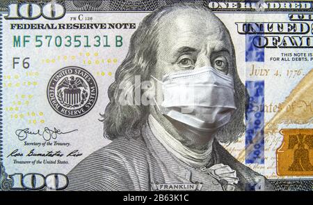 COVID-19 coronavirus negli Stati Uniti, 100 dollari di denaro fattura con maschera facciale. Il coronavirus colpisce il mercato azionario globale. Economia mondiale colpita dal focolaio del virus corona Foto Stock
