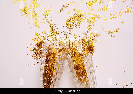 Schizzi di stelle d'oro da un vetro figurativo di vetro su un delicato sfondo beige. Layout pronto per le congratulazioni Foto Stock