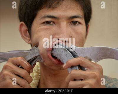 Thai Chinese Taoist devotee (mAh song) pierces la sua guancia destra con lame affilate durante il Phuket Vegetarian Festival (Nine Emperor Gods Festival). Foto Stock