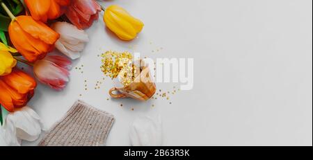 Banner primaverile. Molti angoli d'oro di stelle sono fuoriusciti da una tazza di porcellana bianca su uno sfondo verde chiaro e liscio. Bouquet di tul multicolore Foto Stock