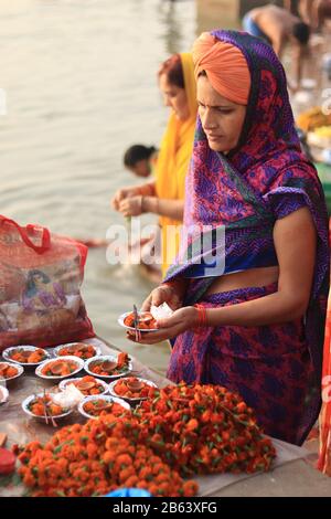 Una donna compra i fiori d'offerta per il fiume santo di Ganga Foto Stock