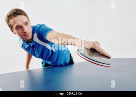 Un giovane giocatore professionista di ping pong che colpisce la palla con la racchetta Foto Stock