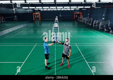 I giocatori professionisti positivi di badminton scuotono le mani dopo aver chiamato il let Foto Stock