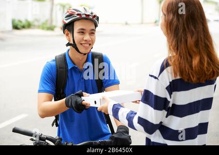 Sorridente bel giovane consegna uomo dare scatola di pizza al cliente femminile Foto Stock