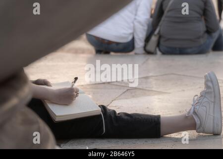 Giovane ragazza che scrive nel suo taccuino sulla piazza del Pantheon a Roma Foto Stock