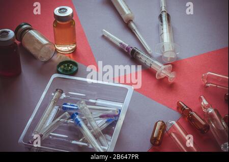 Medicinali, siringhe, fiale sul tavolo. Farmaci sparsi casualmente nella tabella. Messa a fuoco in background. Primo piano. Messa a fuoco selettiva. Senza Foto Stock