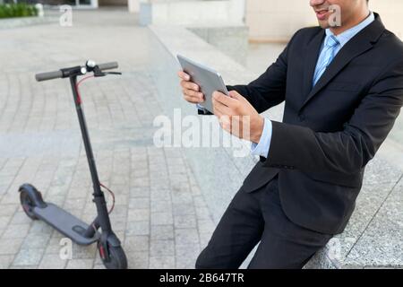 Immagine ritagliata di un uomo d'affari positivo lettura articolo con cattive notizie sul computer tablet Foto Stock