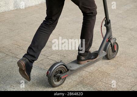 Immagine ritagliata di un giovane uomo che guida in strada su un calcio elettrico scooter Foto Stock