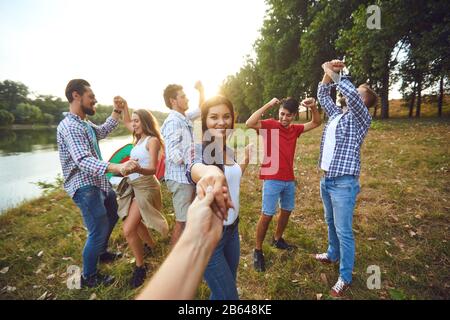 Gli amici hanno divertimento che corre lungo il lago su un picnic. Foto Stock