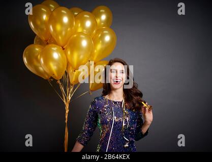 Bella donna con palloncini d'oro in studio girato Foto Stock