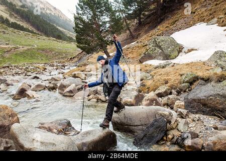 Hiker attraversare il fiume di montagna Foto Stock