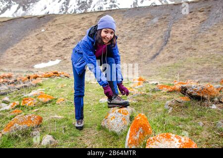 Hiker che stringe i lacci dello scarpone sulla roccia, in alto in montagna Foto Stock