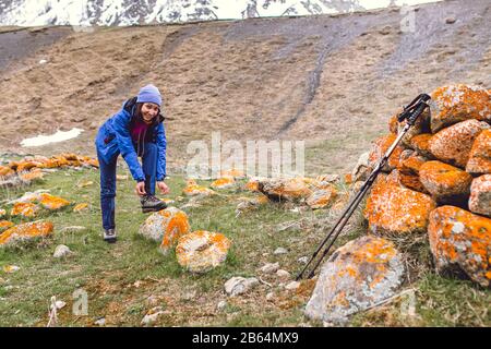 Hiker che stringe i lacci dello scarpone sulla roccia, in alto in montagna Foto Stock