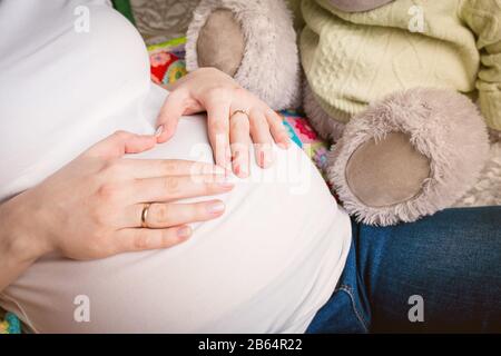 Mani di papà sulla pancia incinta della mamma Foto Stock