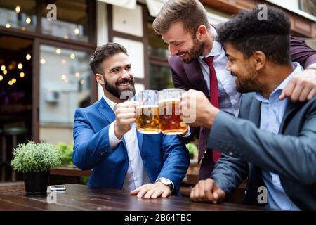 Persone, uomini, tempo libero, amicizia e celebrazione concetto. Amici maschi felici che bevono birra al pub Foto Stock