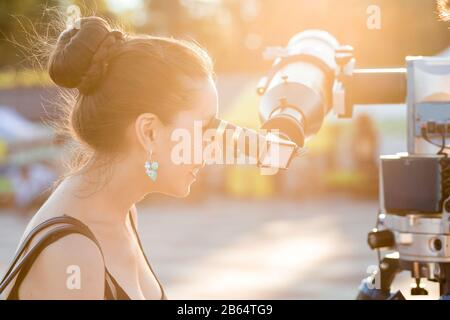 Giovane donna sorridente che guarda verso il cielo attraverso il telescopio astronomico Foto Stock