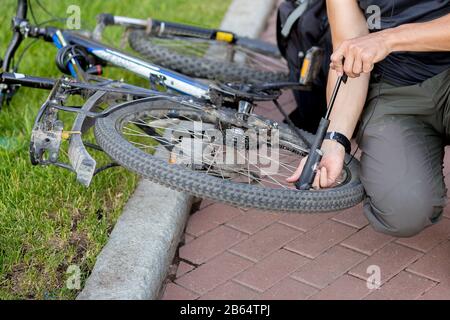 L'uomo pompò la ruota della bicicletta Foto Stock