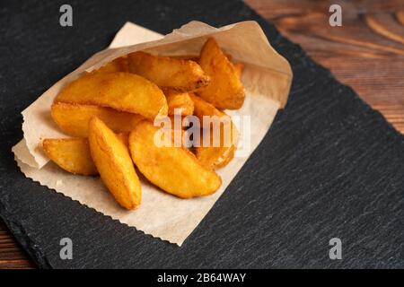 Vasellame rustico di patate ardesia, pietra nera su sfondo di legno. Primo piano. Foto Stock