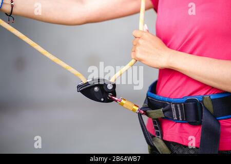 Attrezzatura da arrampicata e fune collegate a un'imbracatura per arrampicatori femmina Foto Stock