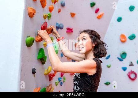 Donna che fa sforzo quando arrampica all'interno Foto Stock