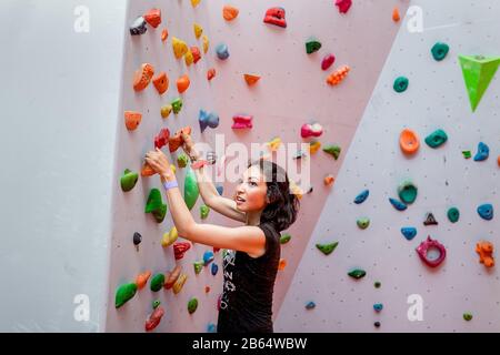 Donna che fa sforzo quando arrampica all'interno Foto Stock