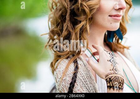 Closeup foto di mani femminili con henné tatuaggio mehndi su abito blu brillante, donna seduta in stile boho indossare, fotografia di stile di bellezza Foto Stock