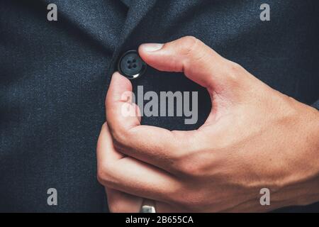 uomo corretto pulsante sulla giacca, mani primo piano Foto Stock