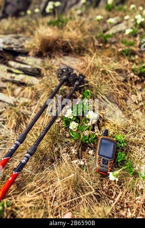 Moderno navigatore GPS professionale e bastoni trekking su erba primavera con sfondo fiori Foto Stock