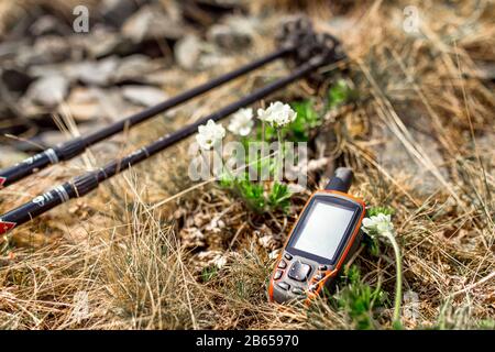 Moderno navigatore GPS professionale e bastoni trekking su erba primavera con sfondo fiori Foto Stock