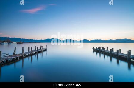 Due pontili in legno o banchine e il lago di sunrise. Torre del Lago Puccini, Versilia, il lago di Massaciuccoli, Toscana, Italia, Europa Foto Stock
