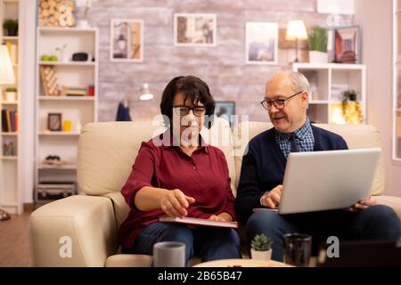 Nonna e nonno usando un computer portatile per chattare con i loro nipoti. Le persone anziane usando tecnologie moderne Foto Stock