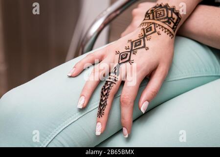 Dipinto a mano con hennè su una gamba donna in salone Foto Stock