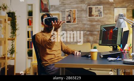 Sviluppatore di giochi con realtà virtuale auricolare fare gesti mano durante la creazione di nuova grafica del gioco. Foto Stock