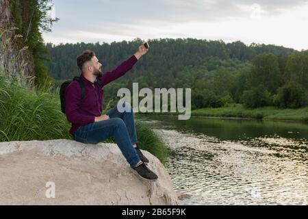 Giovane viaggiatore hippster maschile ribassata che fa selfie. Avventura, vacanza, turismo, internet, tecnologia concetto. Foto Stock