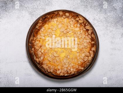 Torta fatta in casa con souffle di formaggio casolare e fiocchi di mandorle su sfondo rustico chiaro. Vista dall'alto. Spazio di copia. Foto Stock