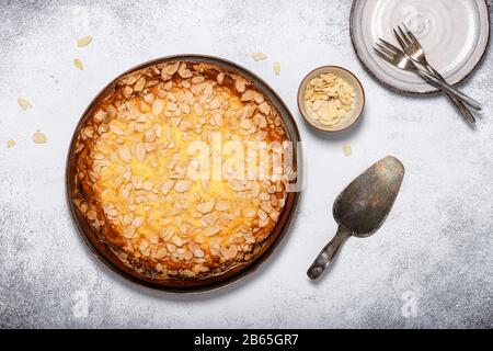 Vista dall'alto della sana torta al formaggio senza glutine con scaglie di mandorle su sfondo rustico. Cucina vegetariana dolce concetto. Foto Stock