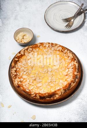 Torta al formaggio appena sfornata con budino alla vaniglia e fiocchi di mandorle su sfondo rustico. Concetto di cibo dolce fatto in casa. Messa a fuoco selettiva. Foto Stock