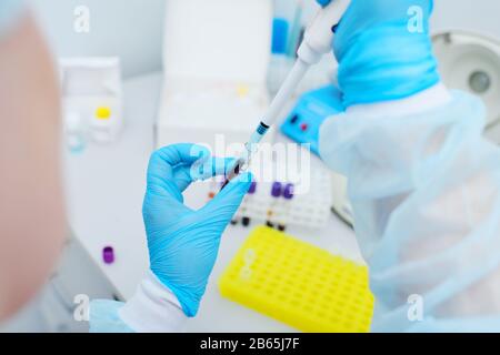 Uno scienziato di laboratorio con un distributore nelle sue mani conduce esperienze o analisi Foto Stock