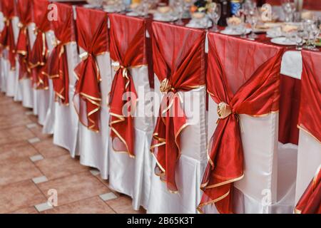 Sedie da matrimonio in fila decorate con nastro di colore rosso Foto Stock