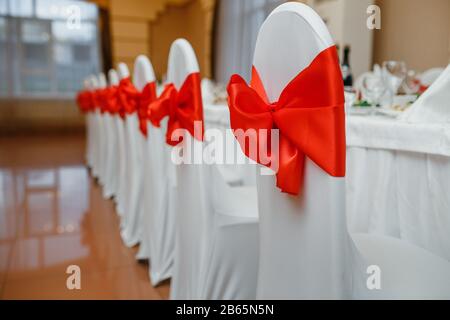 Sedie da matrimonio bianche con archi rossi Foto Stock