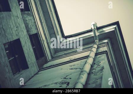 Un'immagine triste e scura di un angolo di un edificio fatiscente con un tubo di scarico e pareti martoriate. Foto Stock