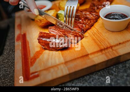 Bistecca di manzo cucinata a medio raro su piatto di legno con forchetta e coltello Foto Stock