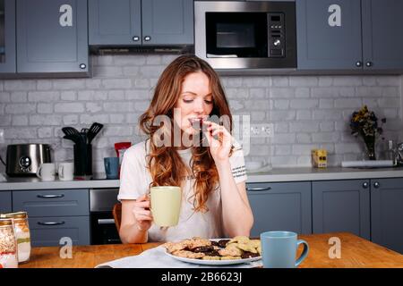 Donna cookie di mangiare e di bere il latte. Carino adorabile giovane e bella modello femminile. Foto Stock