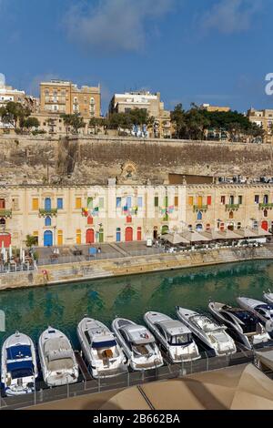 Barche ormeggiate di fronte alla Valetta Quayside sotto Le Mura fortificate di Tall, in una piccola Marina nel Grand Harbour. Foto Stock