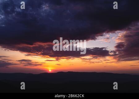 Bellissimo paesaggio di montagna al tramonto. Sole naturale e orizzonte scuro Foto Stock