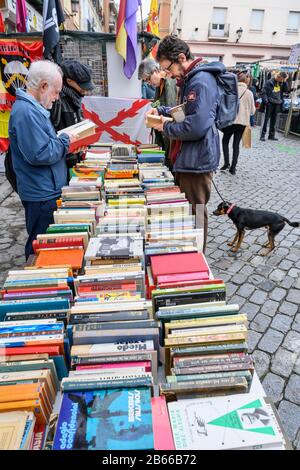 Cacciatori di occasioni che esplorano libri nel mercato delle pulci Rastro intorno alla Plaza de Cascorro tra la Latina e Embajadores, Madrid, Spagna. Foto Stock