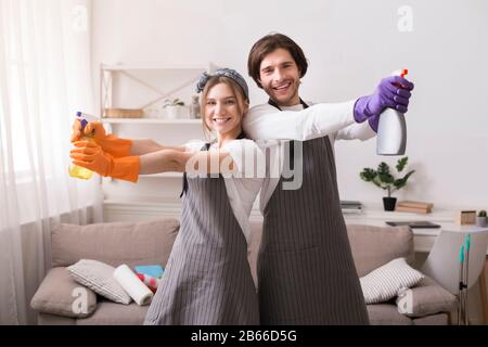 Concetto Di Houskeeping. Felice coppia che tiene detergenti spray, posa in casa interna Foto Stock