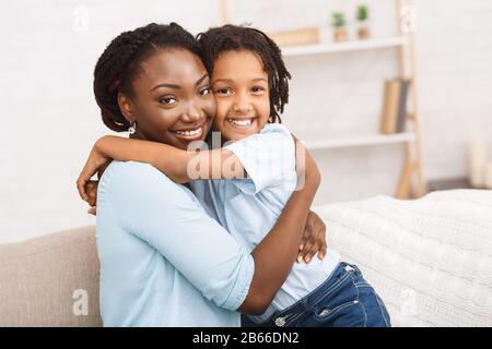 Madre nera e figlia abbracciando a casa Foto Stock